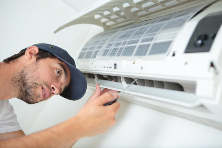 Air conditioning engineer inspecting and servicing a wall mounted air conditioning unit